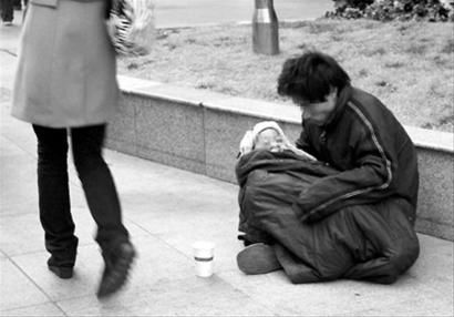 一男子抱着孩子沿街乞讨.晚报 贺佳颖 现场图片